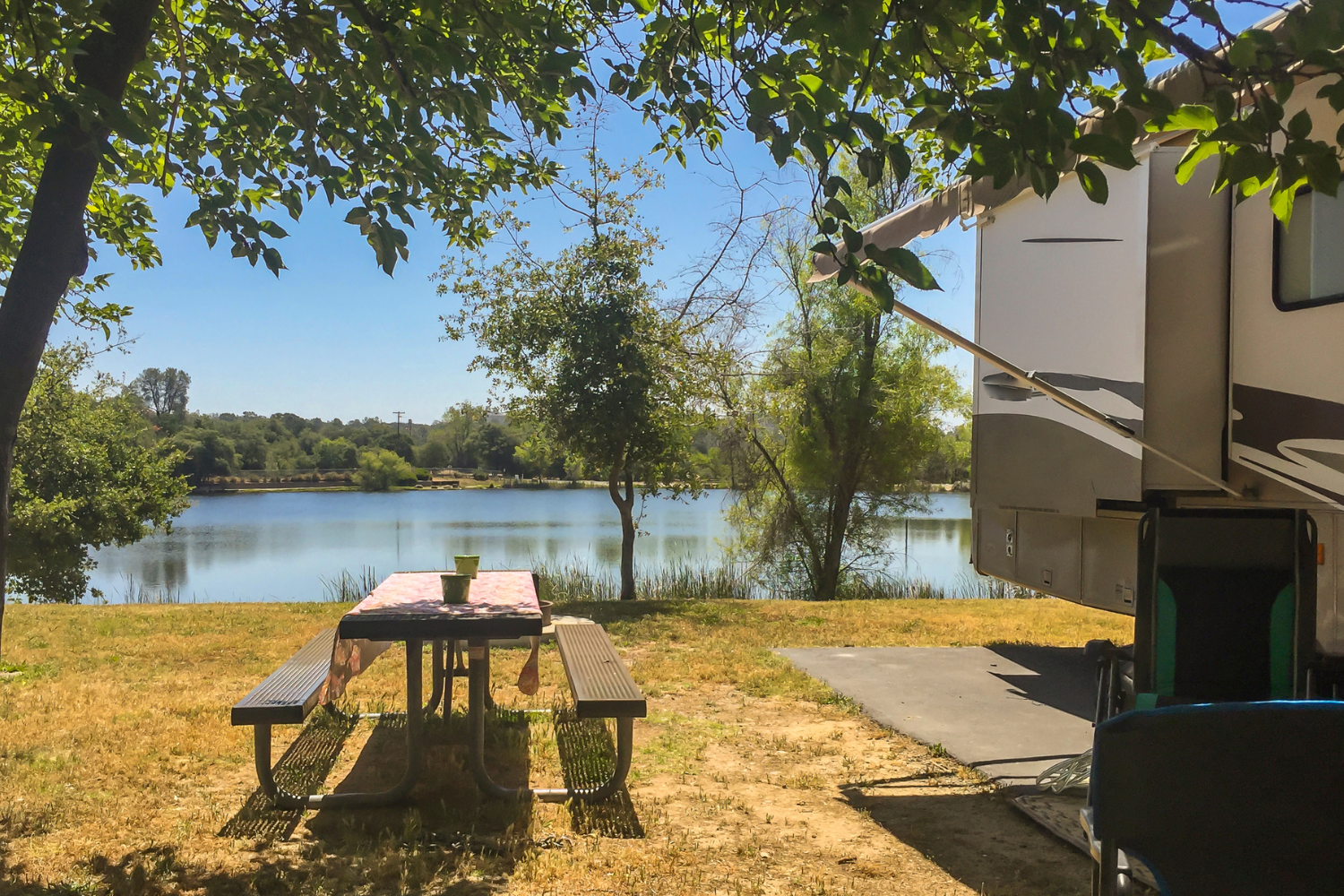 An RV parked by a quiet lake